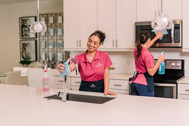 A pair of Molly Maid professionals cleaning a kitchen.